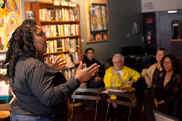 A speaker stands before a small audience.